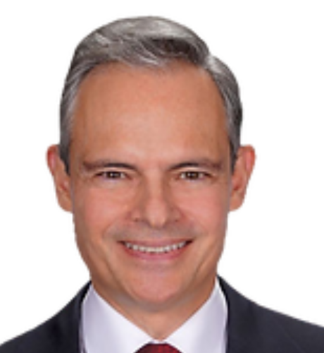 Professional headshot of a smiling executive in a suit, representing leadership and expertise in healthcare and investment sectors.
